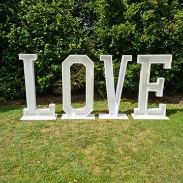 Large white letters spelling 'LOVE' on a grassy area with trees in the background